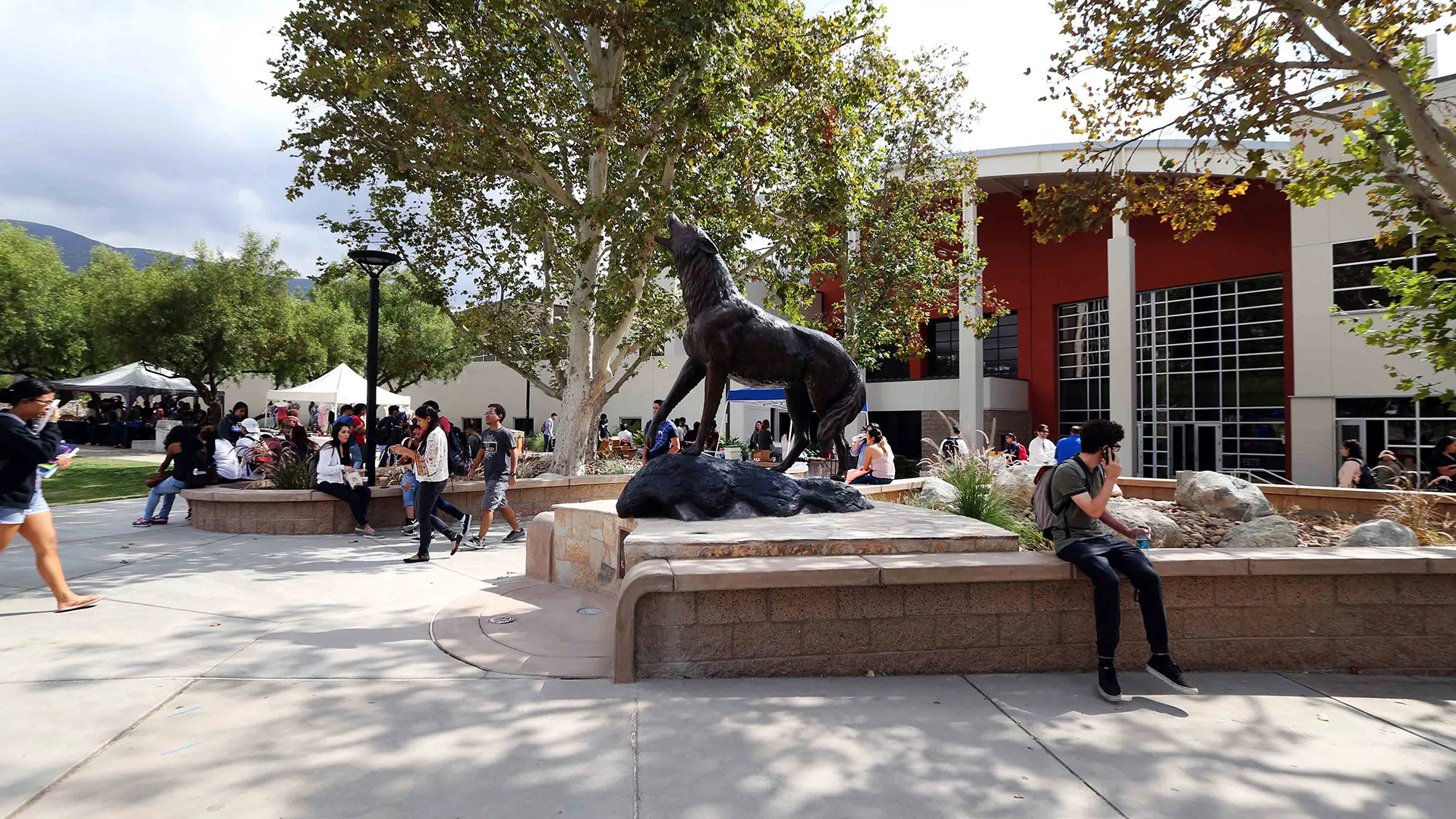 Photo of students on campus, at the Wild Song stature